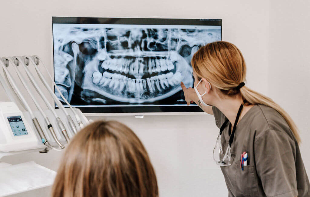 Zahnärztin zeigt einer Patientin eine Röntgenaufnahme der Zähne.