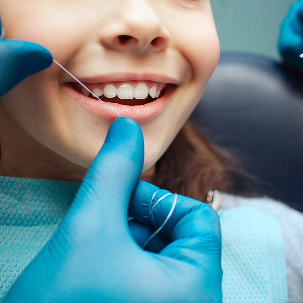 Kind erhält eine professionelle Zahnreinigung mit Zahnseide beim Zahnarzt